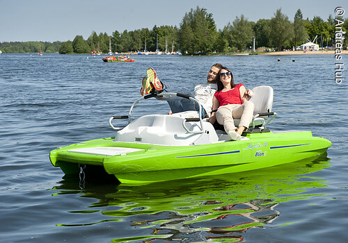 Ein Paar genießt die Sonne auf einem Pedelec-Tretboot am kleinen  Brombachsee. Da in dem Boot ein kleiner Elekromotor eingebaut ist, können die beiden ganz ohne Anstrengug auf dem See fahren.