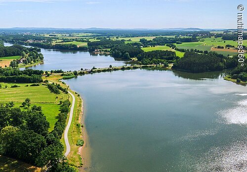 Luftbild von einem Teil des Rothsees. Der See ist umgeben von grünen Wiesen. Entlang des Ufers wachsen viele Bäume und Sträucher.