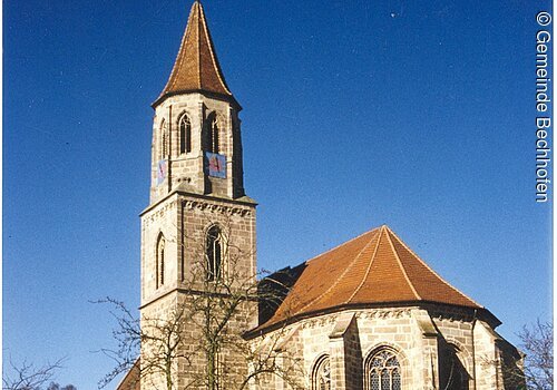 Eine große Kirche mit Kirchturm. Im Hof liegt Schnee.