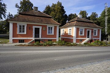 Zwei fast identische barocke Häuschen nebeneinander. Beide mit roter Fassade. Beide mit Mansardendächern.