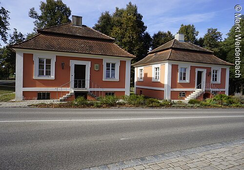 Zwei fast identische barocke Häuschen nebeneinander. Beide mit roter Fassade. Beide mit Mansardendächern.
