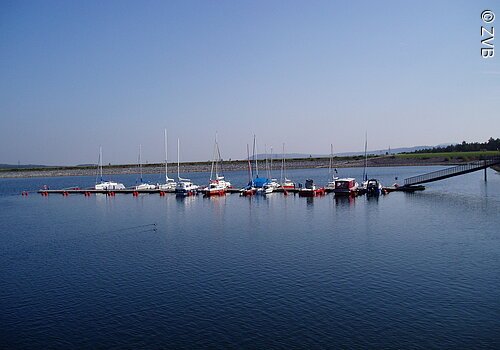 Ein Segelhafen im blauen See. Nur wenige Boote liegen im Hafen.
