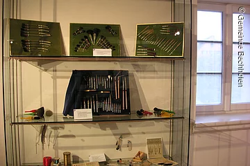 Verschiedenste Pinsel und Bürsten ausgestellt in einer Glasvitrine mit drei Ebenen.
