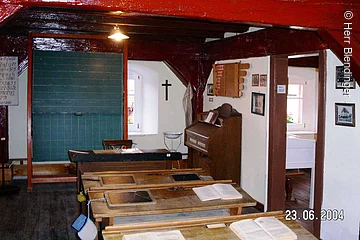 Ein alter Schulraum im Heimatmueseum Merkendorf. Ein Raum in welchem vier alte Schulbänke aus Holz hintereinander in einer Reihe stehen. Ganz vorne eine grüne Kreidetafel.