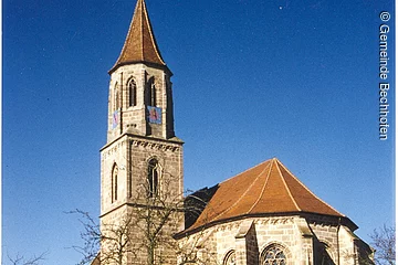 Eine große Kirche mit Kirchturm. Im Hof liegt Schnee.
