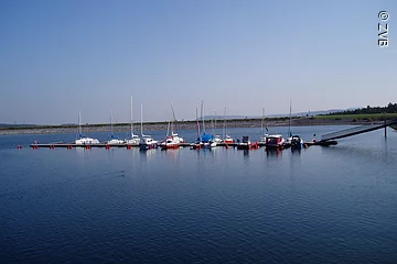 Ein Segelhafen im blauen See. Nur wenige Boote liegen im Hafen.