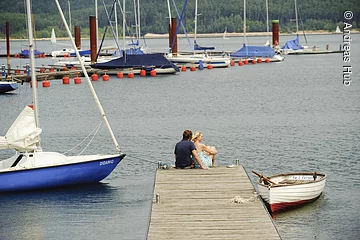 Auf dem Steg des Ramsbergers Segelhafens am Brombachsee genießen zwei Verliebte die wunderschöne Aussicht auf den Brombachsee und die Segelschiffe.