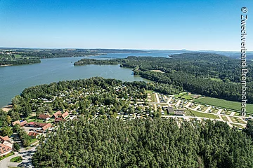 Ein Luftbild des Brombachsees. Der See ist umgeben von Wald. Im vorderen Teil des ein Campingplatz.