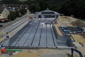 Auf dem Bild ist das Becken und das Gebäude des Freibades zu sehen