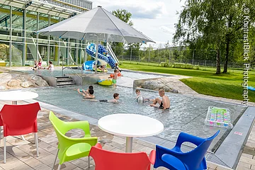 Außenbereich des Sport- und Freizeitbades Greding mit Planschbecken, Wasserrutsche und Sitzgelegenheiten