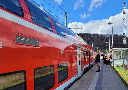 Eine Regionalbahn hat am Gleis gehalten und Reisende warten darauf, dass sich die Türen öffnen.